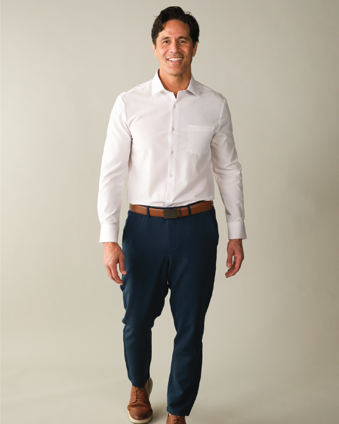A wearing a white dress shirt, with pocket, brown belt, and blue pants