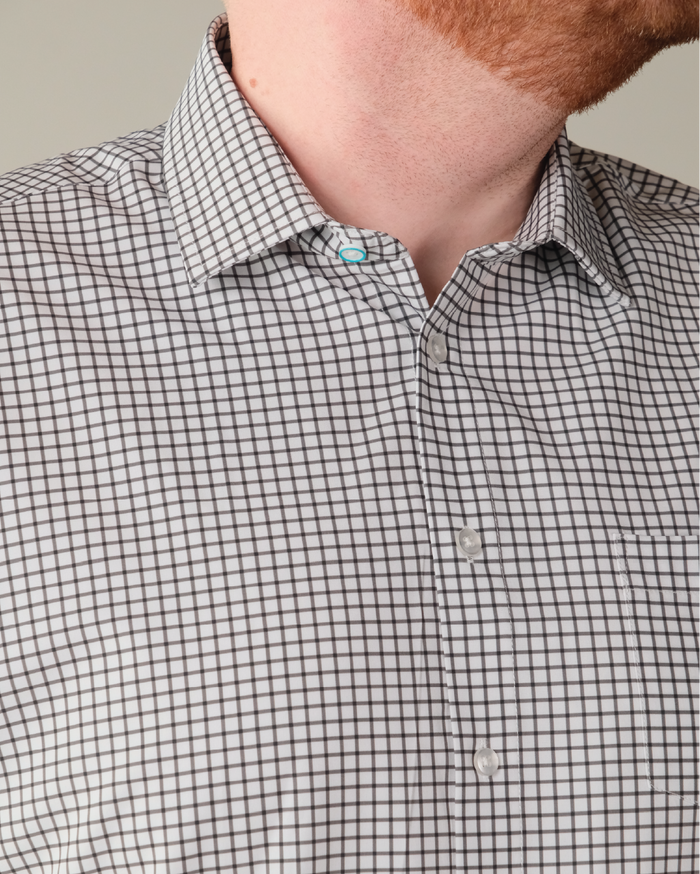 Man wearing white with black check shirt. Top button has blue ring.