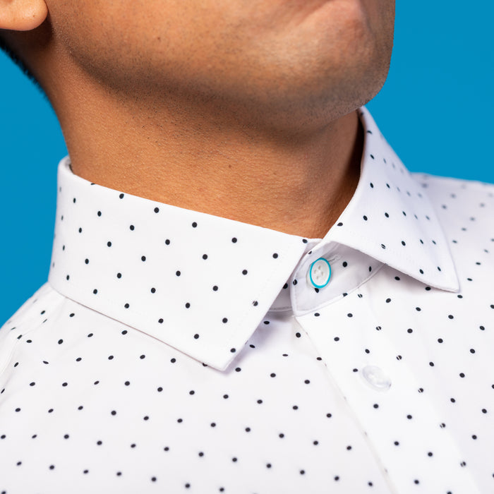 Man wearing a white shirt with navy polka dots, blue coloring top button ring