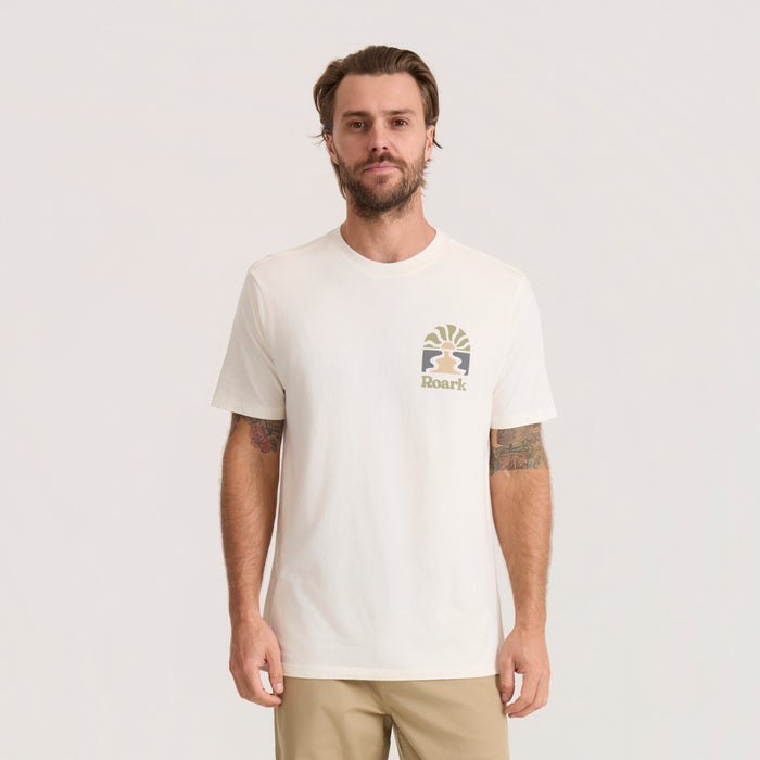 Cream colored Roark Roaming Premium Tee with small logo graphic on chest, worn by bearded man against neutral background