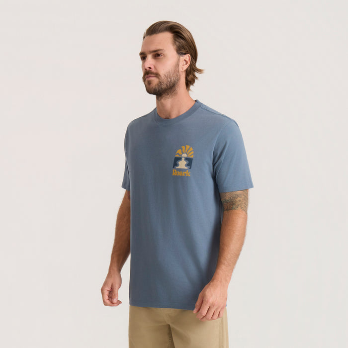 Slate blue Roaming Premium Tee with small gold and navy logo on chest, worn by man in three-quarter view against neutral background