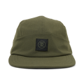 Olive green camper hat with woven texture and black branded patch on front, displayed on white background