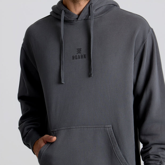 Active person wearing a Roark hooded sweatshirt, designed for adventure and travel, in a dynamic outdoor setting.