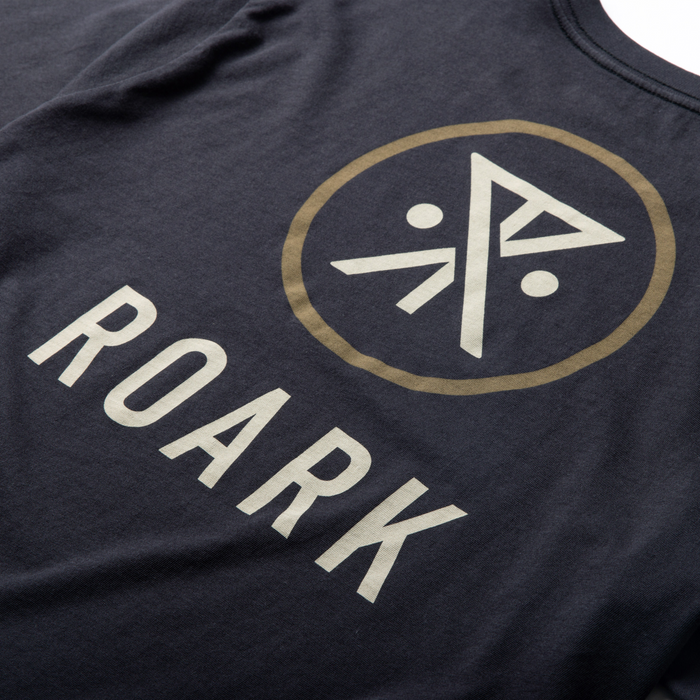 Charcoal black Roark short sleeve tee with cream and tan geometric logo and text graphic on chest, flat lay detail