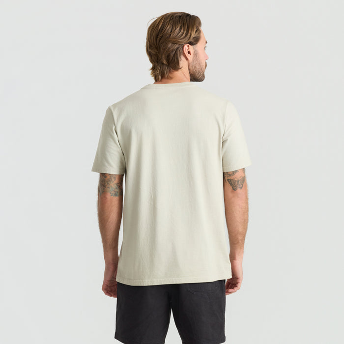 Active man standing in a field wearing a Roark adventure-ready active shirt, focusing on sleeve and shoulder design details.