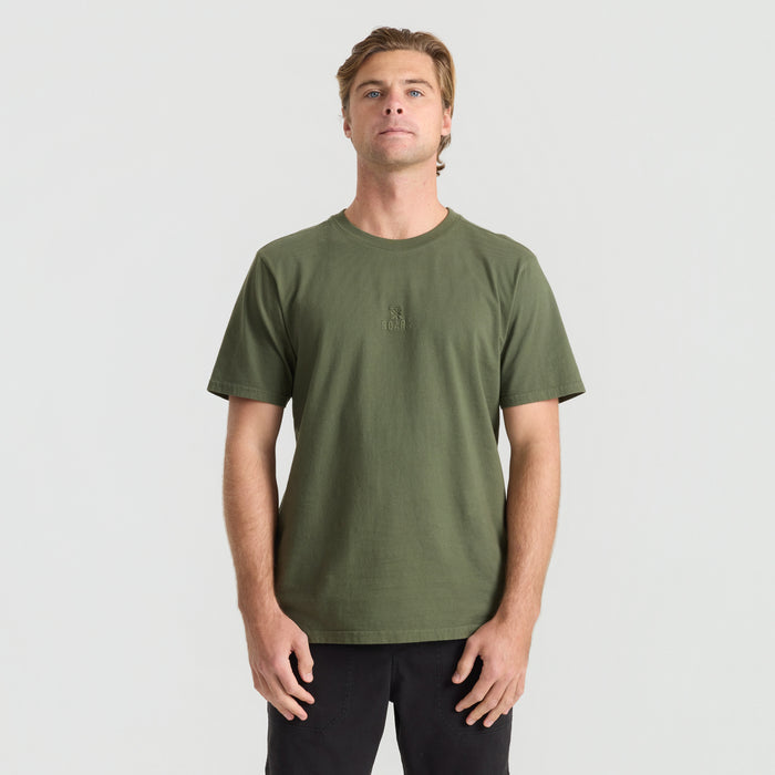 Active person standing in a durable Roark military-style shirt, showcasing its rugged design perfect for travel and outdoor adventures.