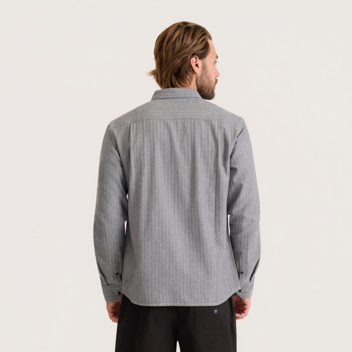 Man wearing gray chambray button-up shirt with long sleeves, shown from back view against neutral background
