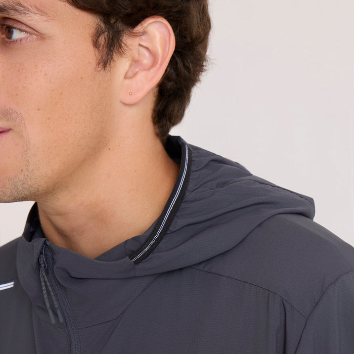 Man wearing dark navy Second Wind Jacket by Roark with drawstring hood and visible piping detail, shown in profile view