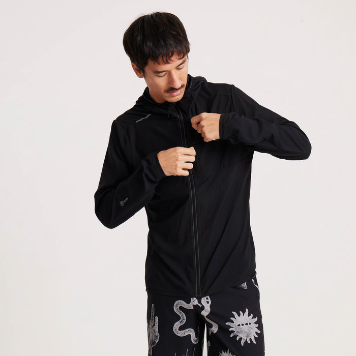 Model zipping up the Roark black windbreaker jacket, highlighting its functional design and comfortable fit for all-weather exploration.