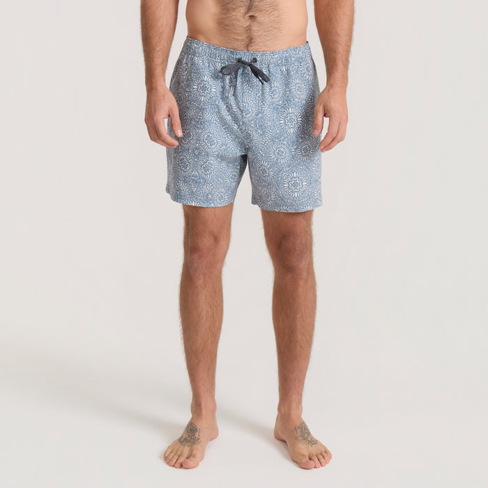 Slate blue Shorey boardshorts with sunflower print and black drawstring, worn by man on neutral background