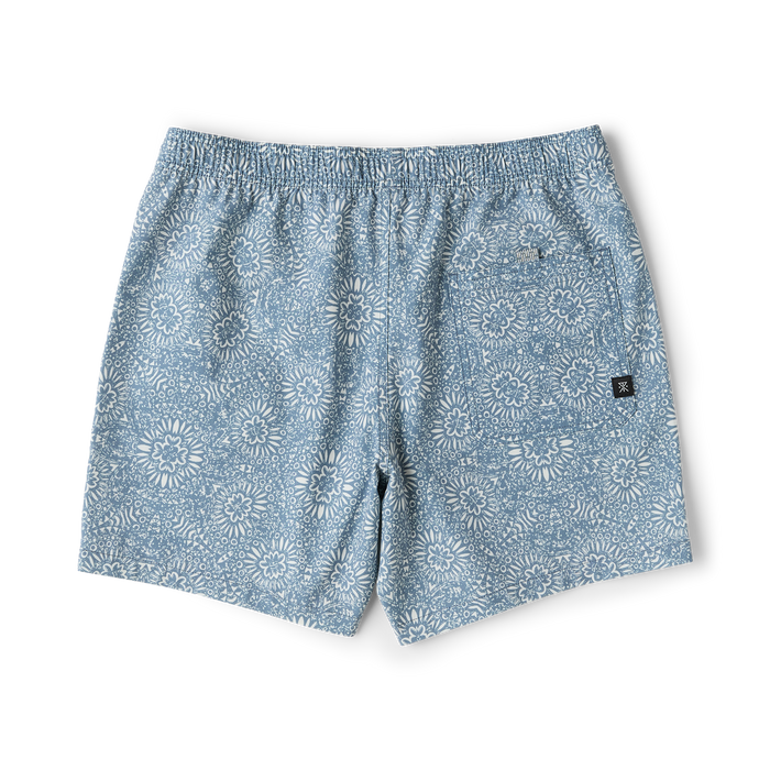 Slate blue boardshorts with all-over sunflower and floral pattern, flat lay on white background