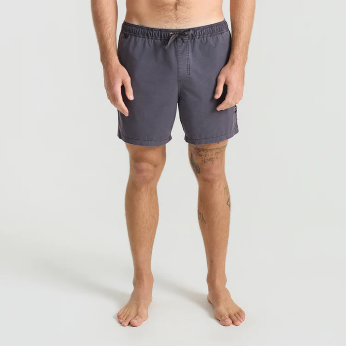 Man wearing Shorey 16" Trunks in washed black with drawstring waist, standing barefoot against neutral background
