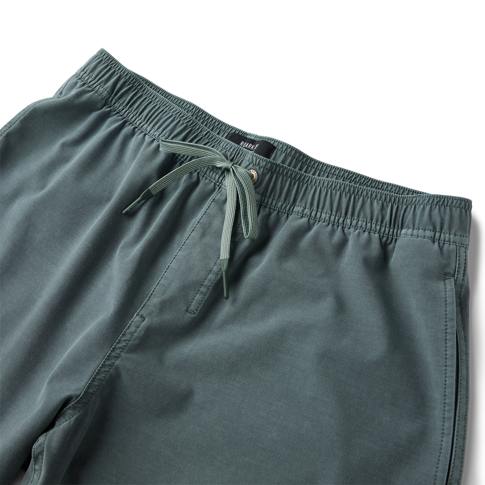 Shorey boardshorts in washed slate green with elastic waistband and drawstring detail on flat lay background