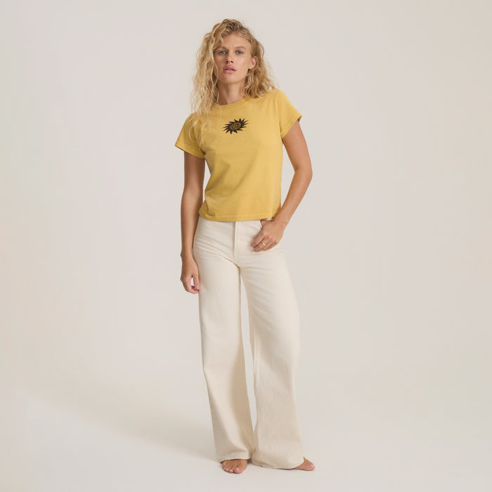 Yellow short-sleeve tee with black sun graphic on model paired with cream wide-leg pants against neutral background