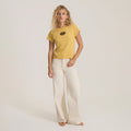 Yellow short-sleeve tee with black sun graphic on model paired with cream wide-leg pants against neutral background