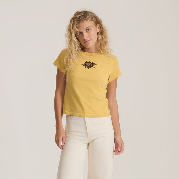 Sunbeam Muse Premium Tee in wheat yellow with black eye graphic, worn by model with cream pants