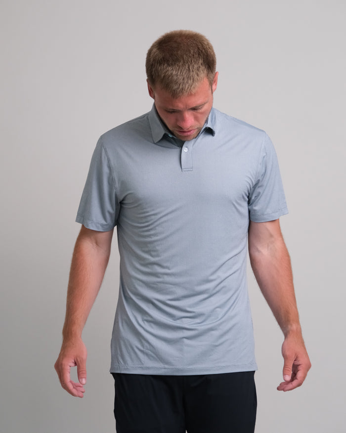 Man wearing  a steel gray short sleeve polo shirt against a gray background