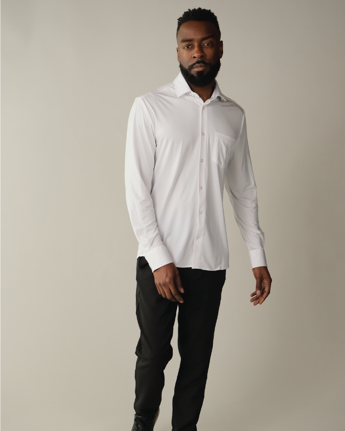 A man wearing a white, long-sleeved, button-up shirt with a collar, against a beige background.