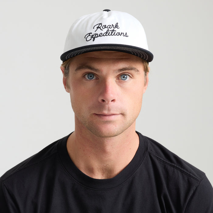 White Roark trucker hat showing intricate logo detail, designed for style and comfort on outdoor adventures.
