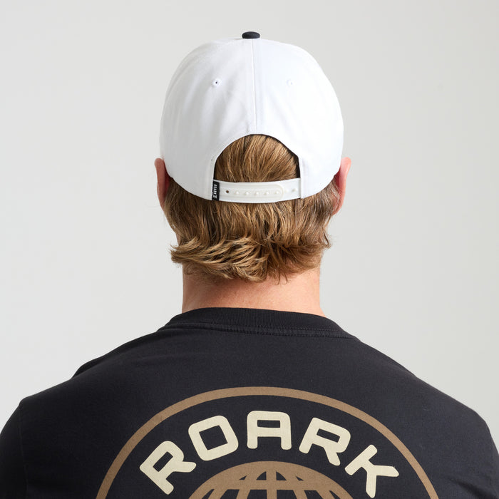 Man wearing white active shirt and cap from Roark's adventure collection, embodying a spirit of travel and outdoor exploration.