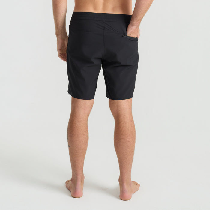 Group of adventurous people in a natural setting wearing Roark's boardshorts and Bermuda shorts, engaging with a calf near tree trunks.