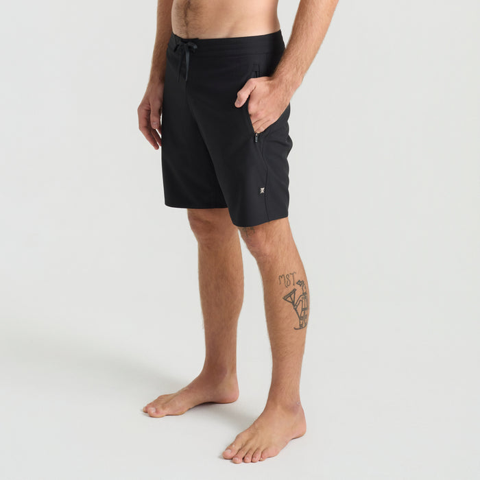 Adventure at the beach with Roark: Calf wearing black boardshorts enjoying leisure time by the shore, barefoot and having fun.