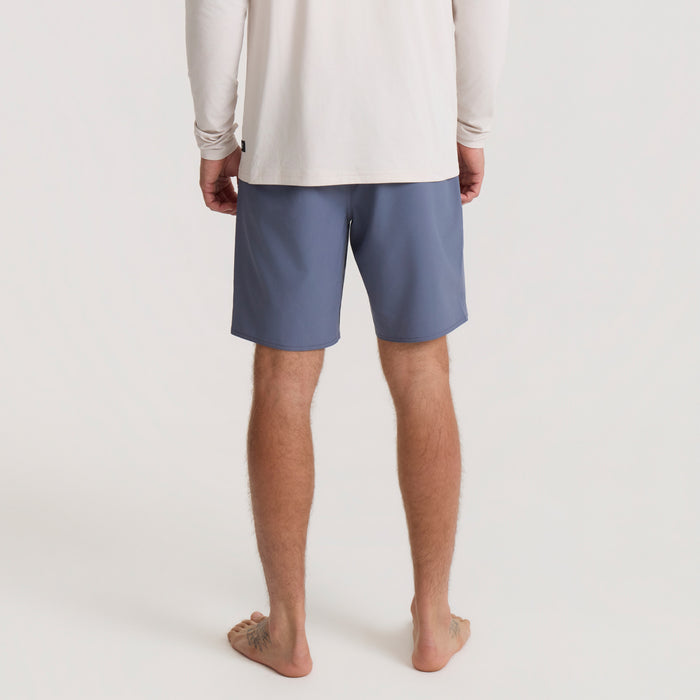 Vacation vibes with sandy calf and foot peeking out of Bermuda shorts on a beach adventure
