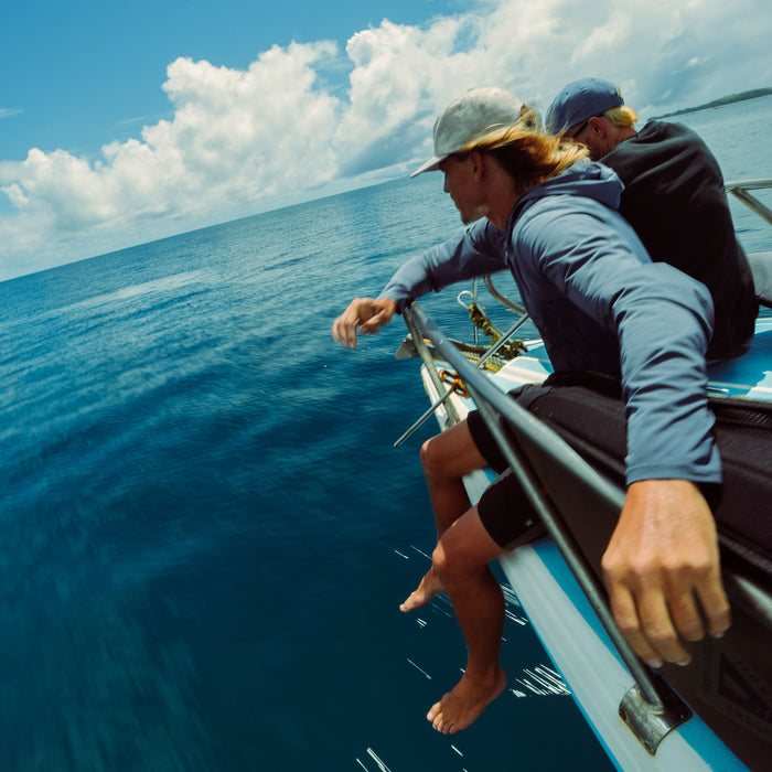 Woman wearing Neptune blue Venture UPF Hoodie while fishing from boat on open ocean with clear sky
