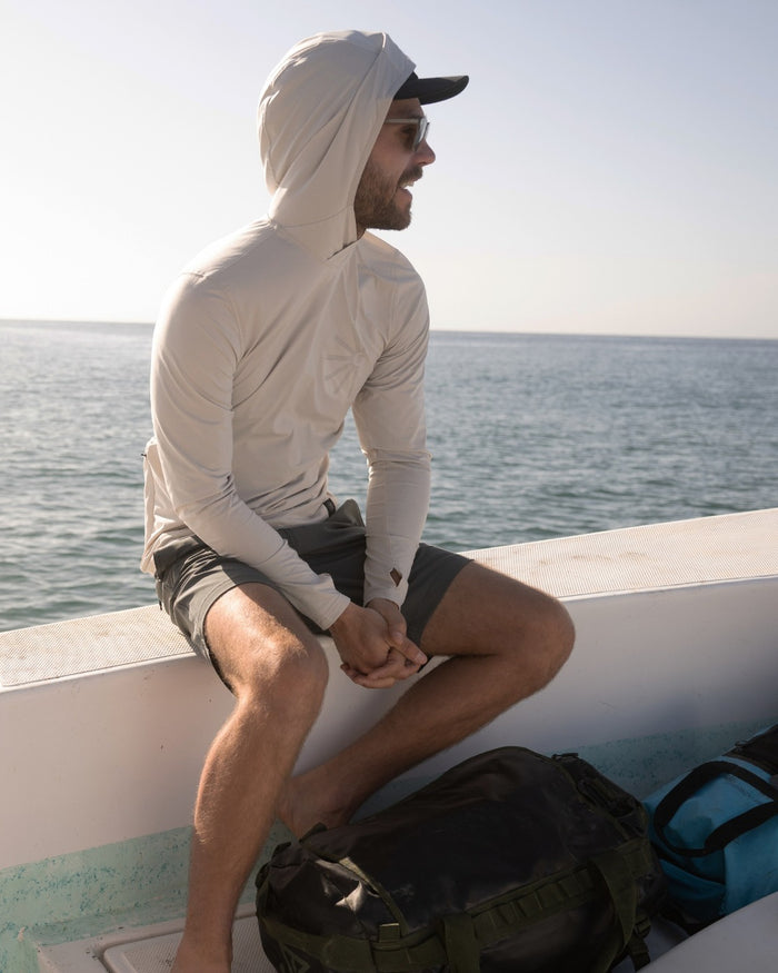Cream-colored Venture UPF Hoodie with hood up on man sitting on boat overlooking ocean water