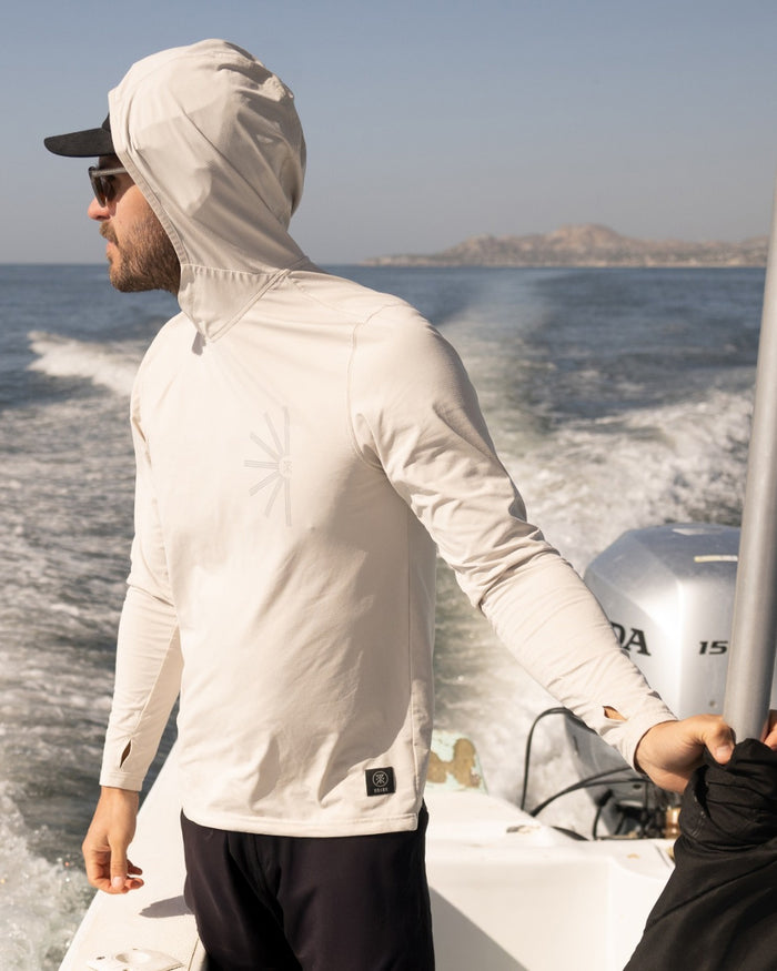 Man wearing off-white Venture UPF hoodie with attached hood on a boat at sea, shown from side view