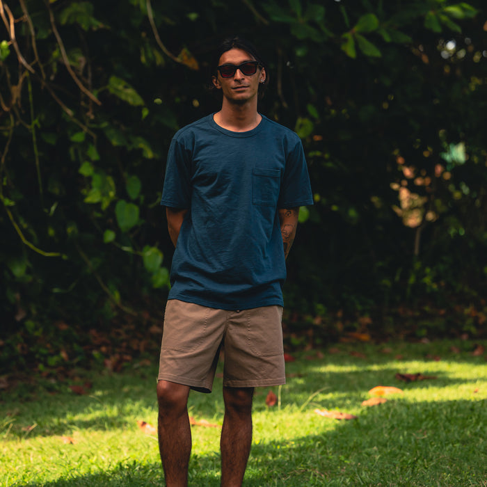 Man wearing Roark shorts and a short sleeve tee, embodying a summer adventure vibe with a focus on comfort and durability in an outdoor setting.