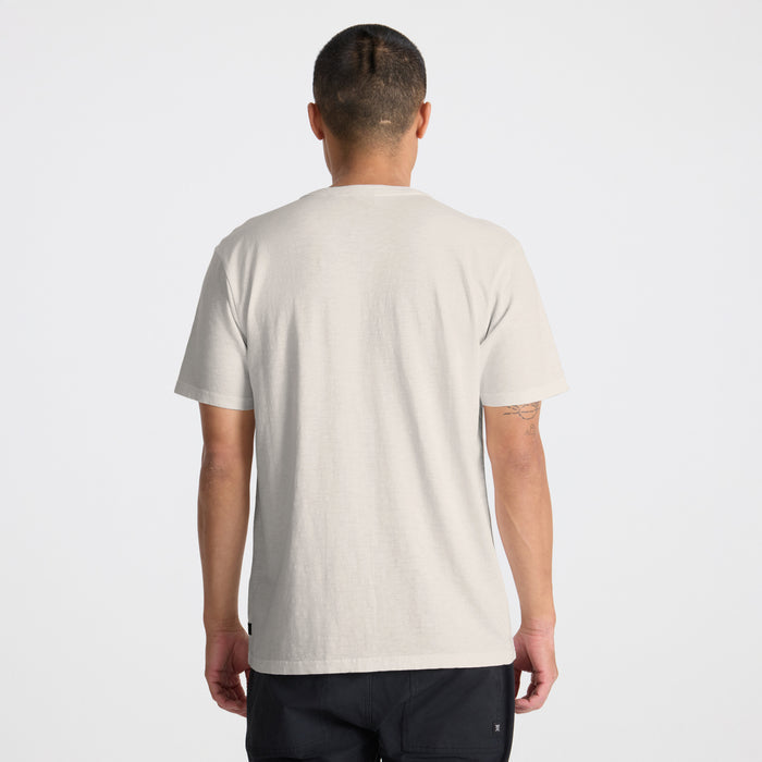 Active man in a Roark adventure shirt, featuring visible sleeve, shoulder, and neck details, standing confidently in an outdoor setting.