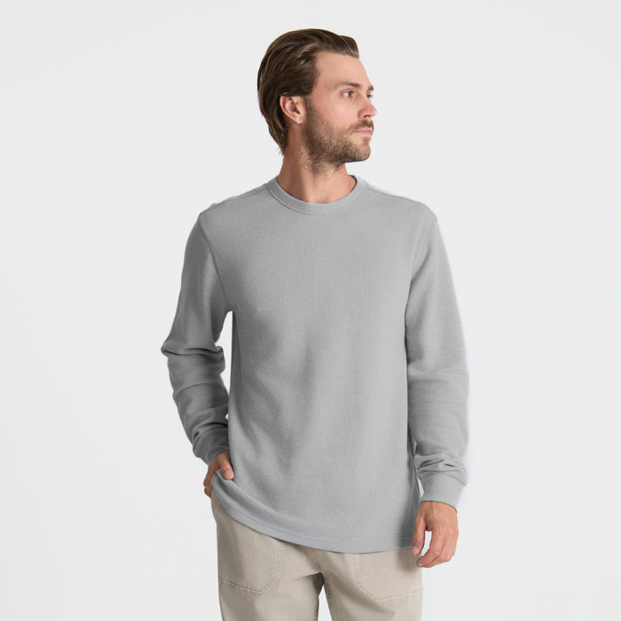 Man wearing a grey long-sleeved active t-shirt designed for outdoor adventures, showcasing durability and comfort in a rugged setting.