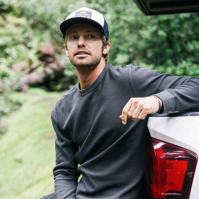 Outdoor enthusiast wearing a Roark Well Worn Thermal Long Sleeve Tee and a stylish hat, ready for a cool weather adventure.